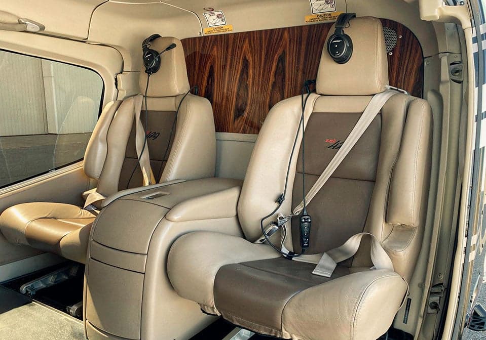 Two tan leather seats with headsets in the helicopter's cabin.
