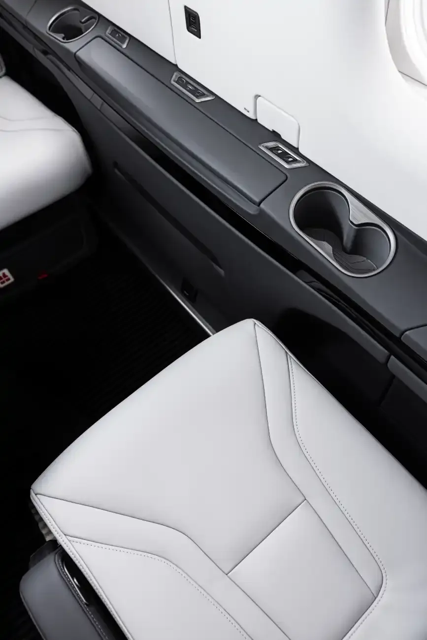Close-up of the aircraft's interior showing a white leather seat and side console with cupholders.