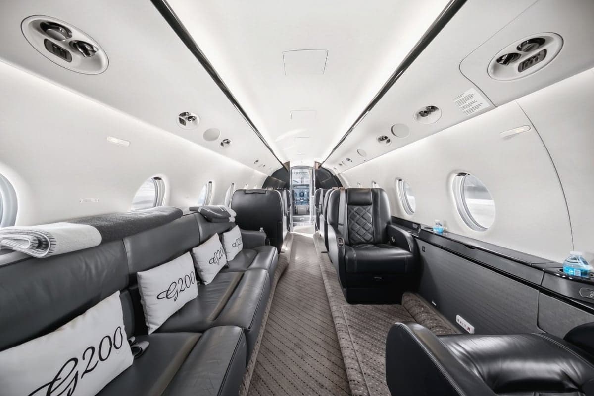 A view of the interior of the aircraft, showing the leather seats and a couch with pillows.