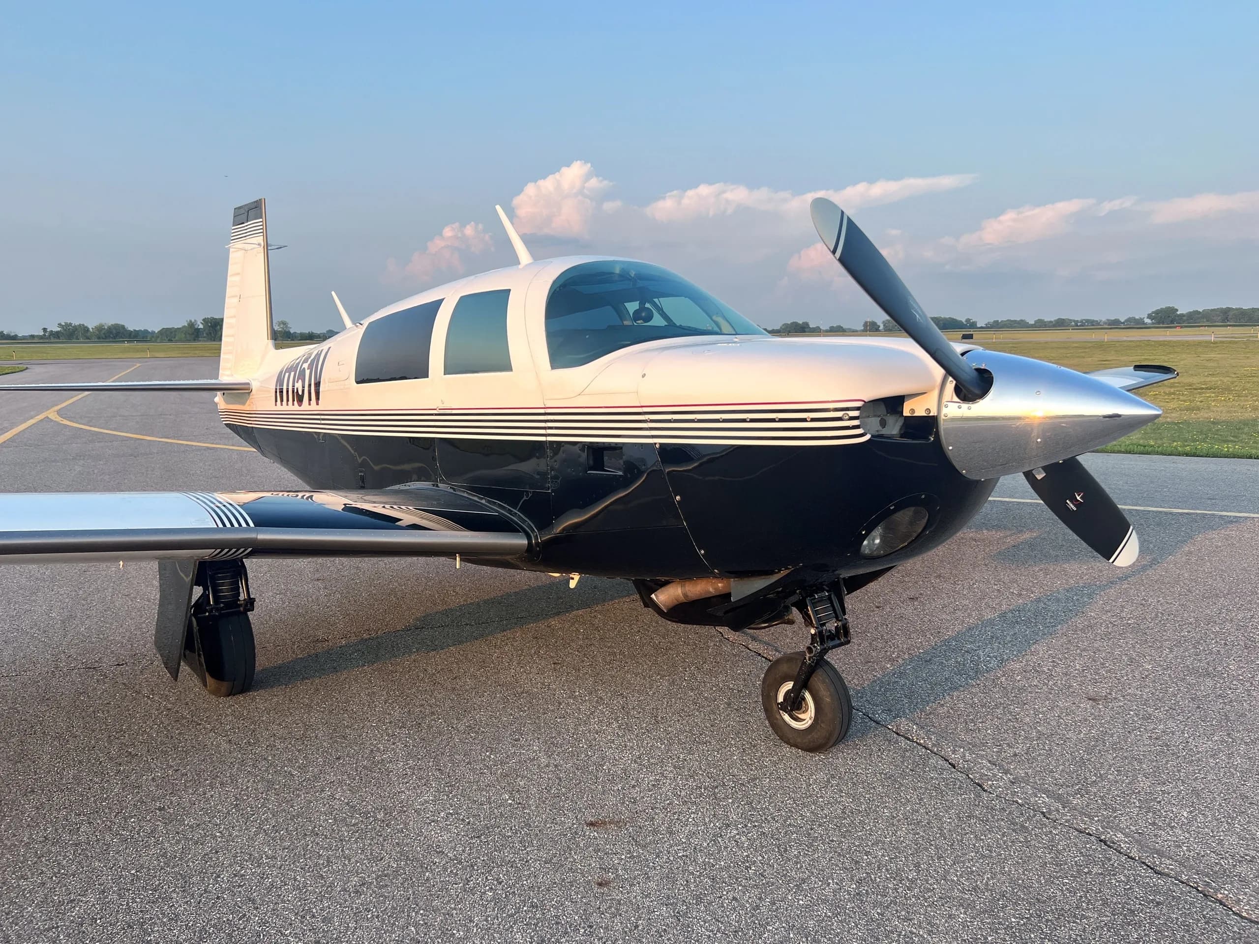 A front-side view of a white and dark blue single-engine aircraft, N1151V, with its propeller slightly blurred.