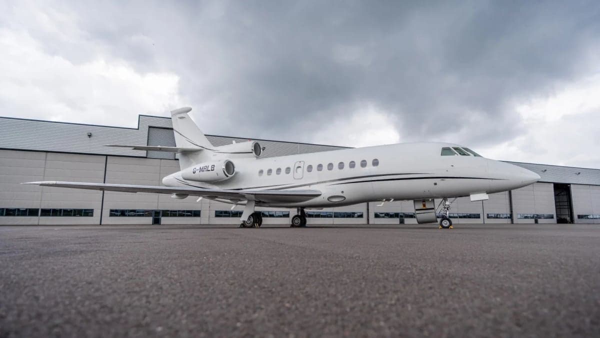 Close-up of the tail section and engines of a white Dassault Falcon 7X business jet.
