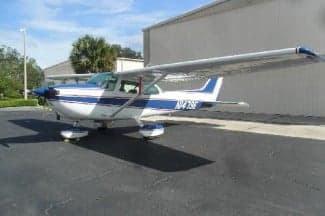 A white and blue Cessna 172 with tail number N1479E is parked on the tarmac.