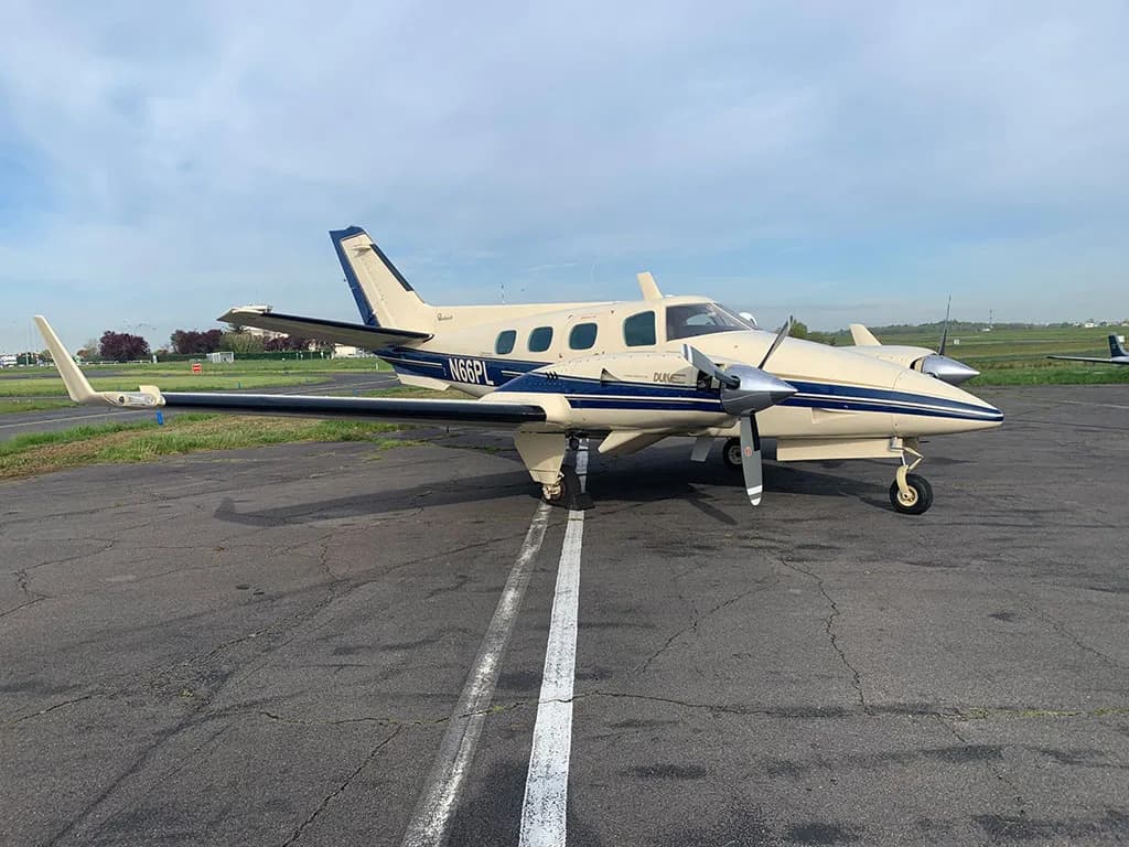 A beige and blue twin-engine Piper PA-31-350 Navajo Chieftain aircraft (N66PL) is parked on an asphalt tarmac.
