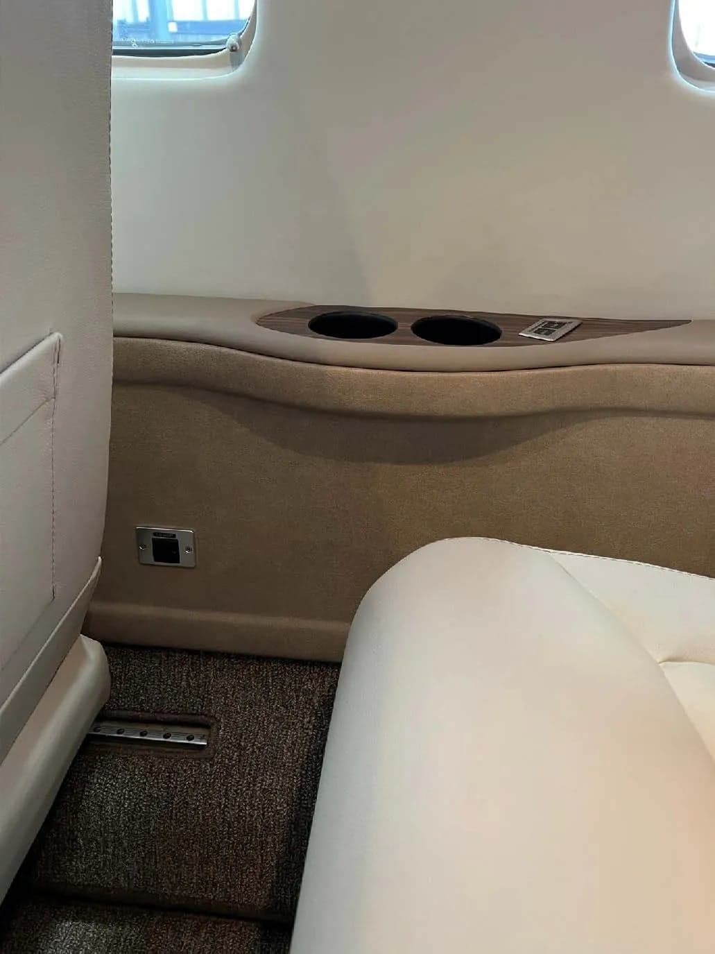 Close-up of the aircraft cabin interior, showing the side panel with cupholders.