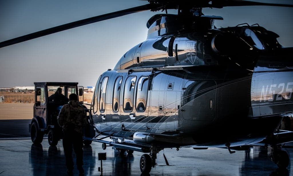 A dark Bell 525 helicopter parked on the tarmac at dusk.