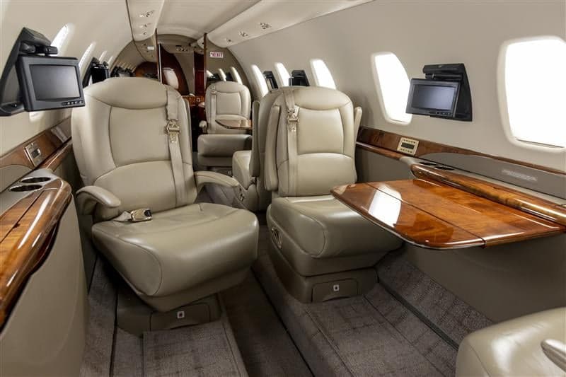 The aircraft's interior features leather seats, wood accents, and individual entertainment screens.