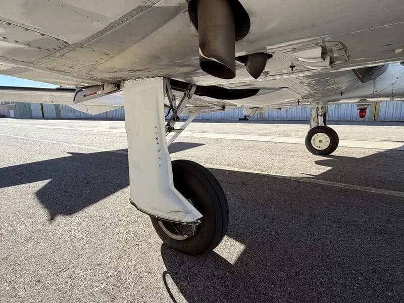 Close-up view of the main landing gear and exhaust pipes of a Cessna 310 aircraft.