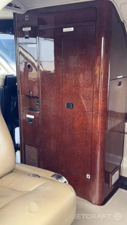 A detailed view of a dark wood veneer cabinet or galley area inside the business jet cabin.