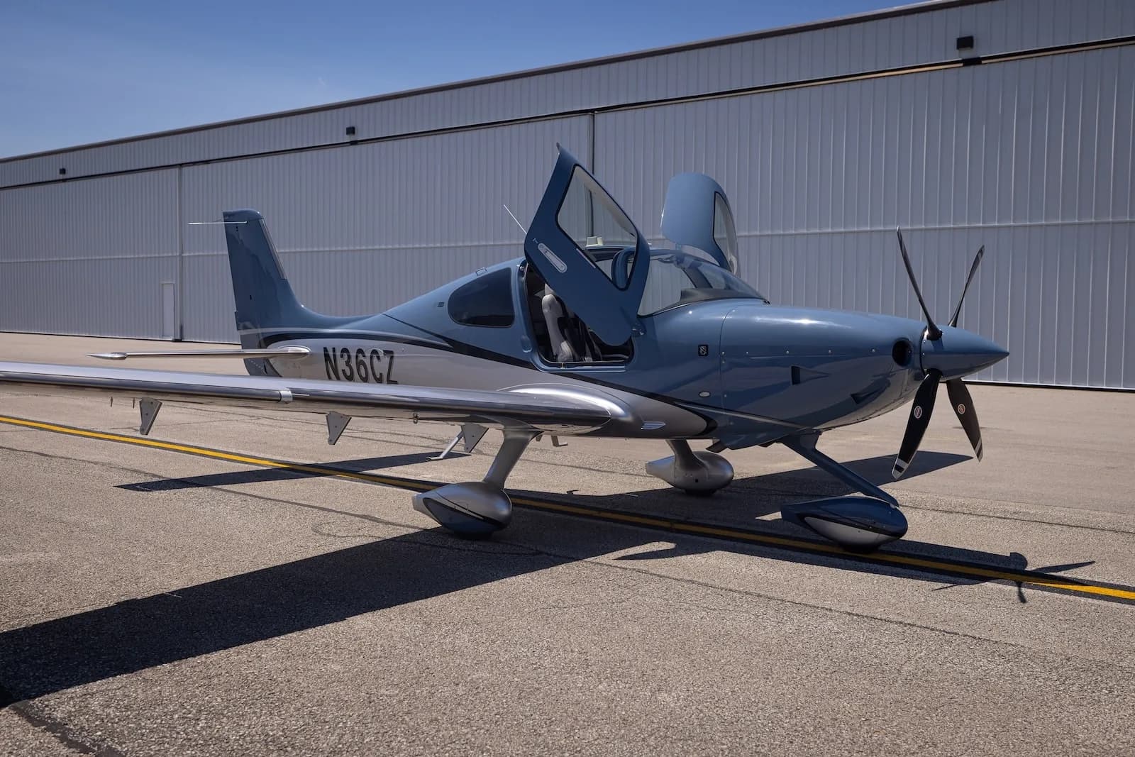 A Cirrus SR22T aircraft with open doors is parked on the tarmac.