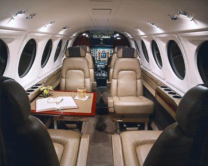 View of the aircraft cabin with leather seats and a table.