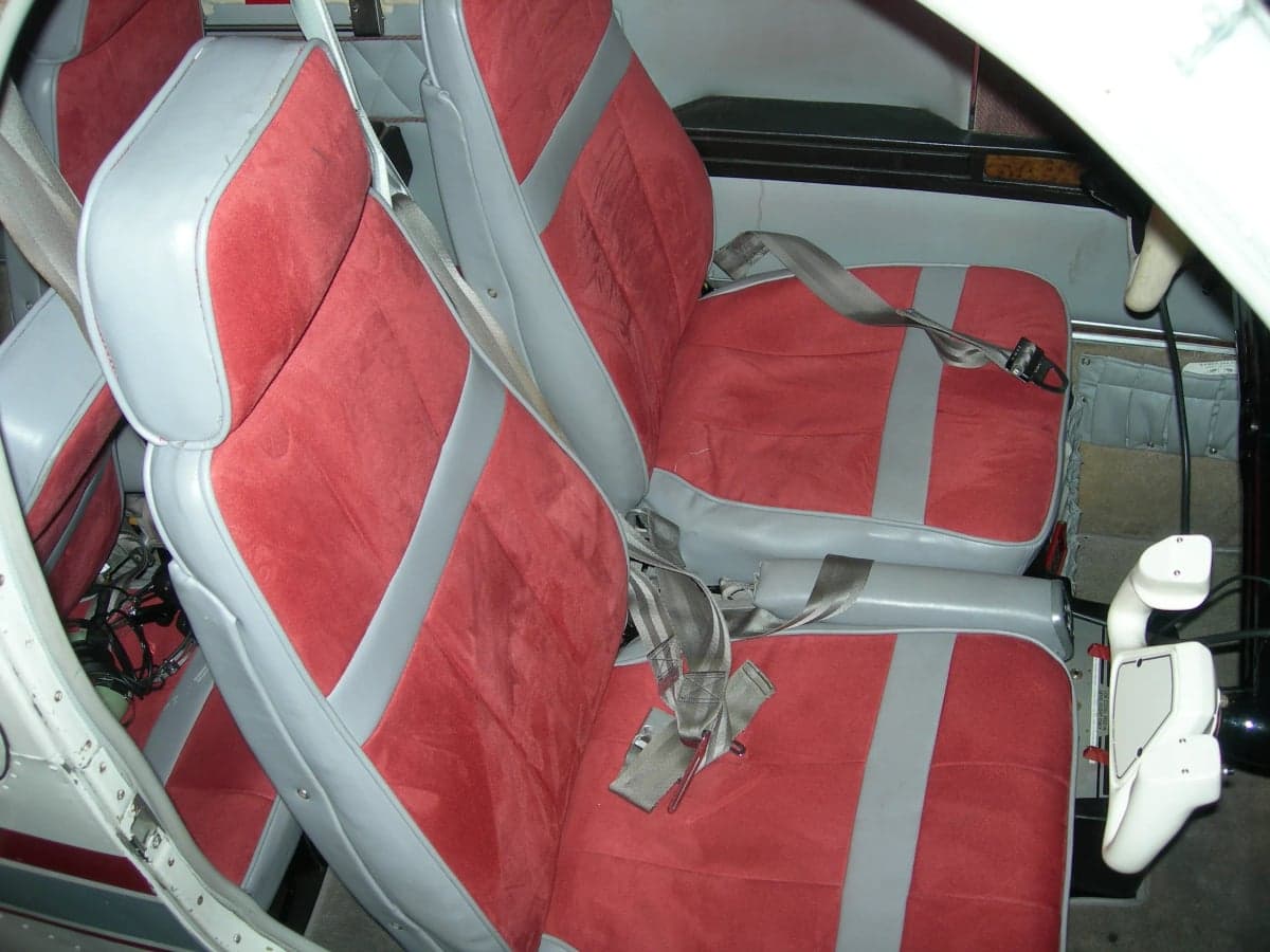 Red and gray aircraft seats with seatbelts.
