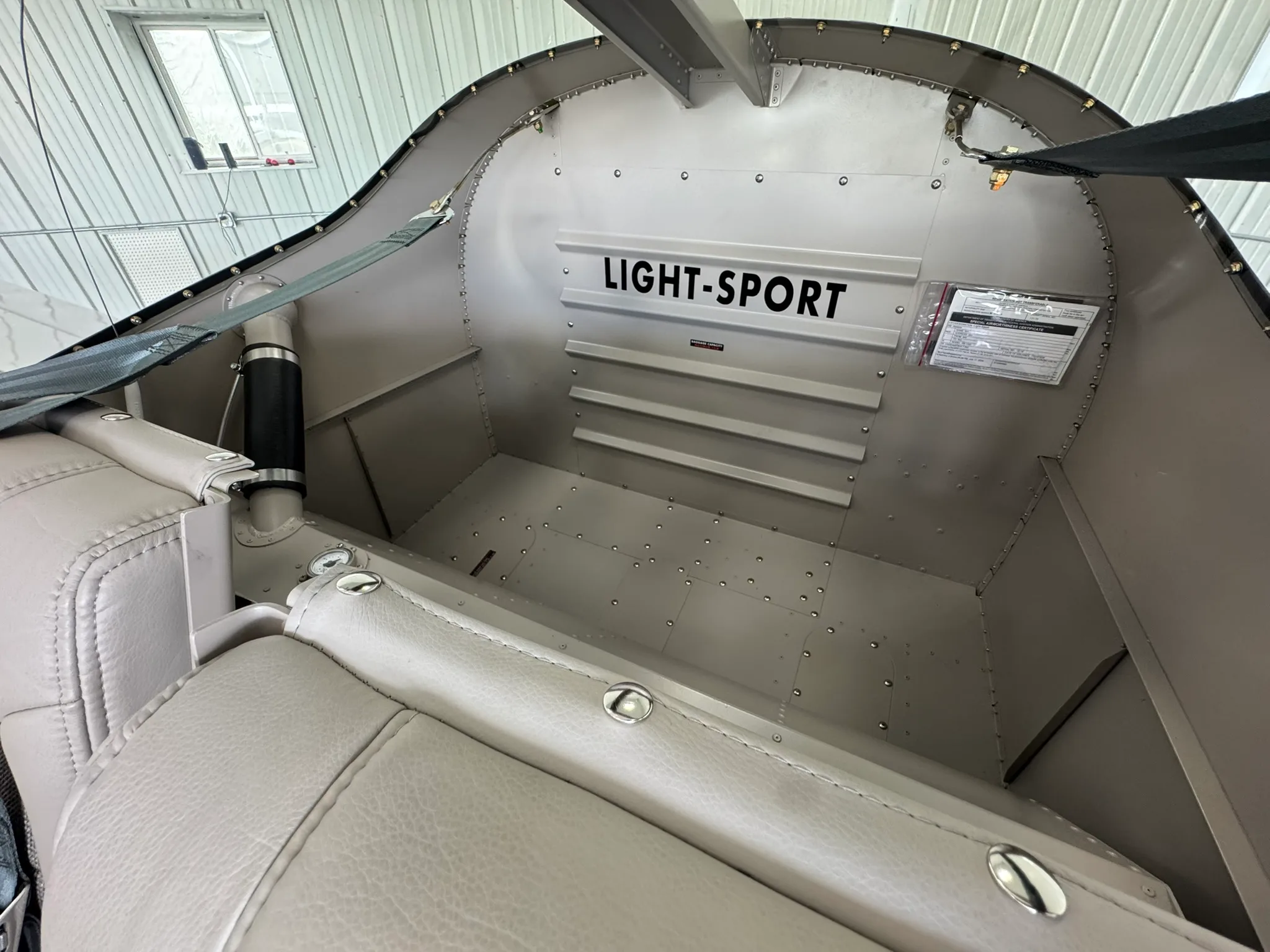 The rear baggage compartment of a light-sport aircraft, showing a metal interior with "LIGHT-SPORT" stenciled on the back wall.