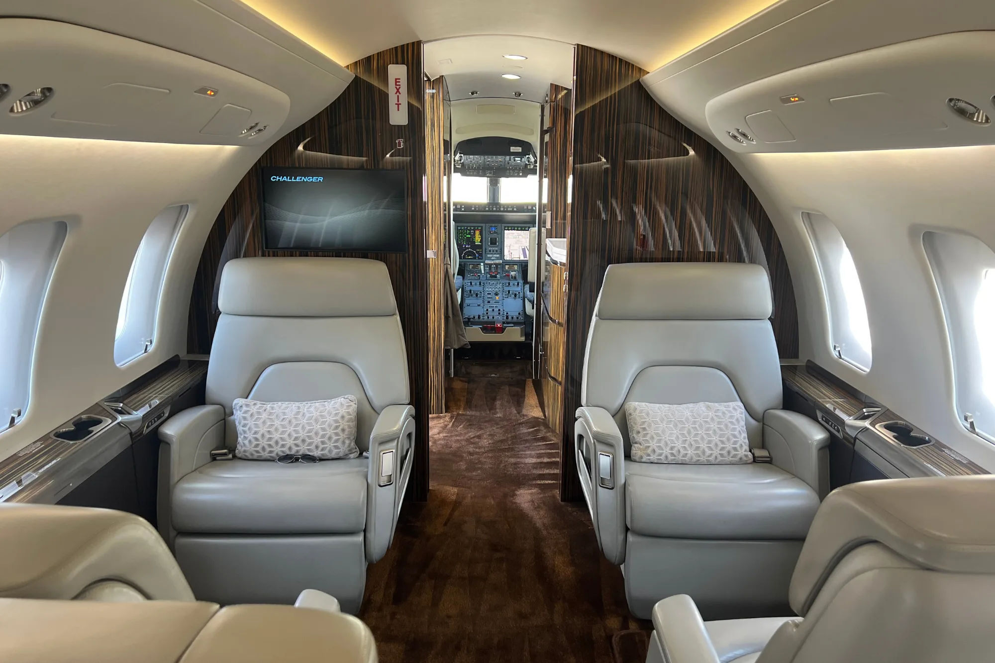 Spacious aircraft cabin with light grey seats and a view into the cockpit.