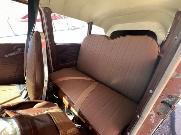 View of the Cessna Skywagon 180's brown fabric rear seats and interior side panel.