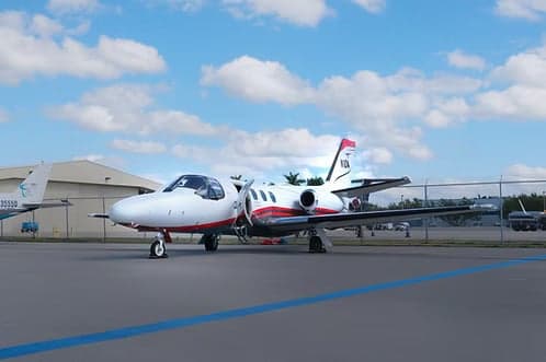 A white and red Cessna Citation Mustang parked on the tarmac.