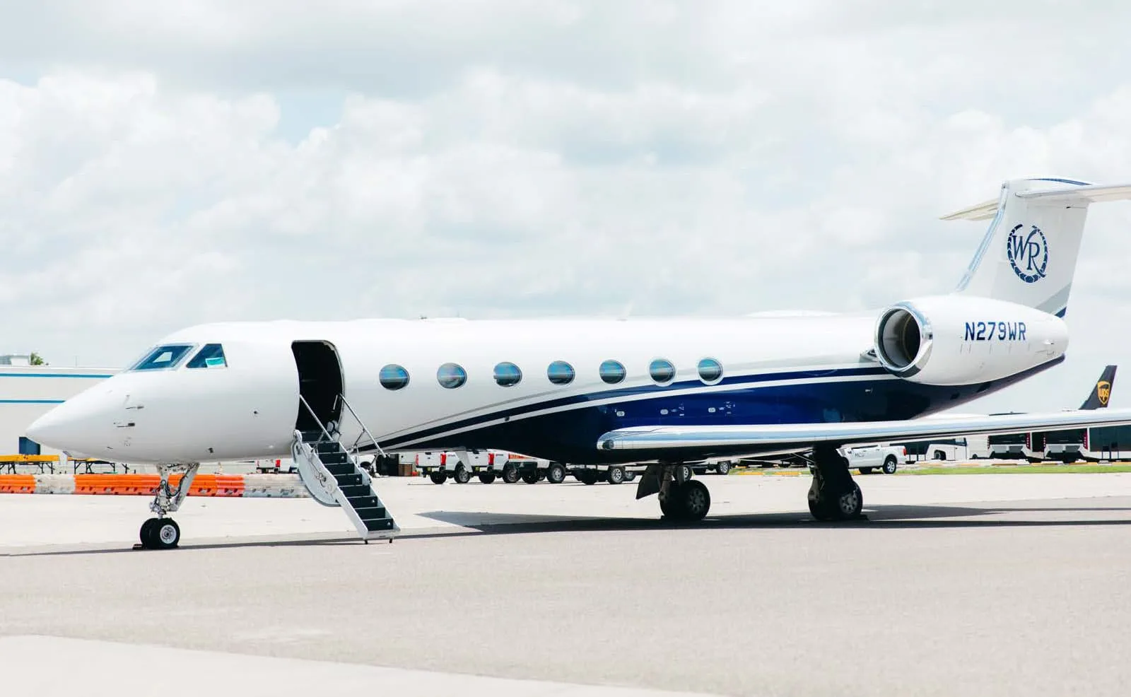 A white and blue Gulfstream G550 business jet, registration N279WR, parked on the tarmac with its main door open.