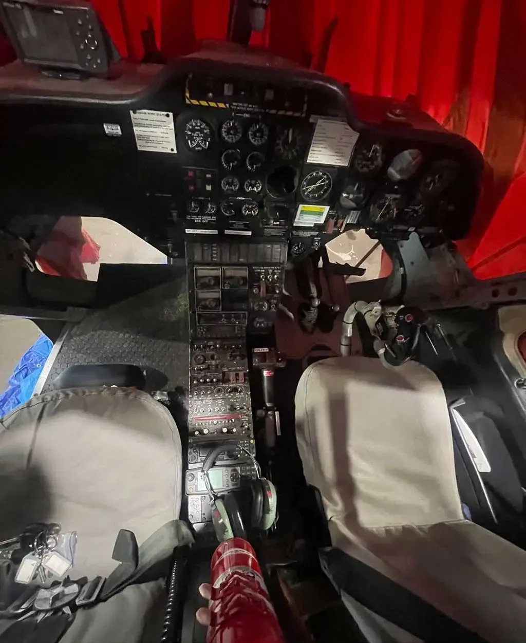 A wide view of a helicopter cockpit showing the instrument panel, controls, and two pilot seats.