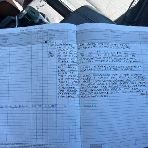 A close-up of a flight record book with handwritten notes and entries.