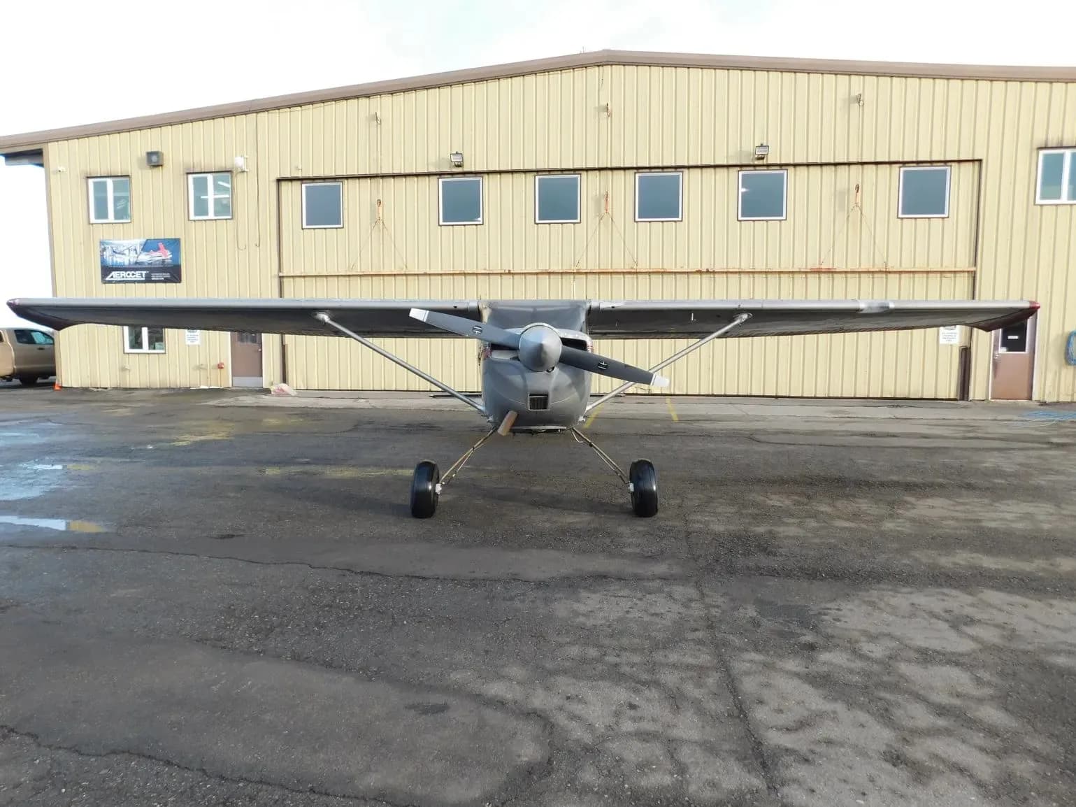 A silver single-engine propeller aircraft (N2861S) parked on a tarmac, viewed head-on in front of a hangar.