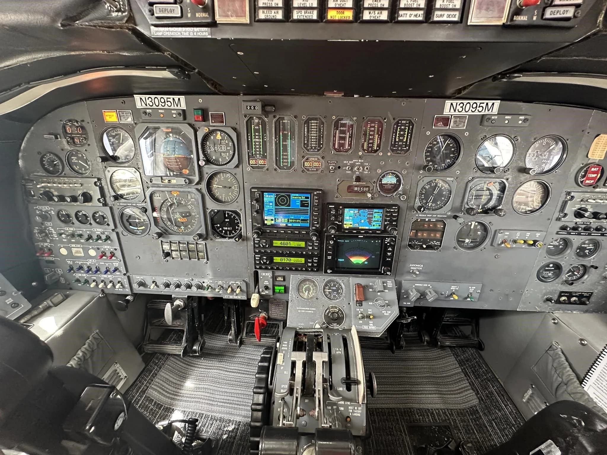 The full cockpit instrument panel of the Cessna Citation jet (N3095M) with analog gauges and modern MFDs.