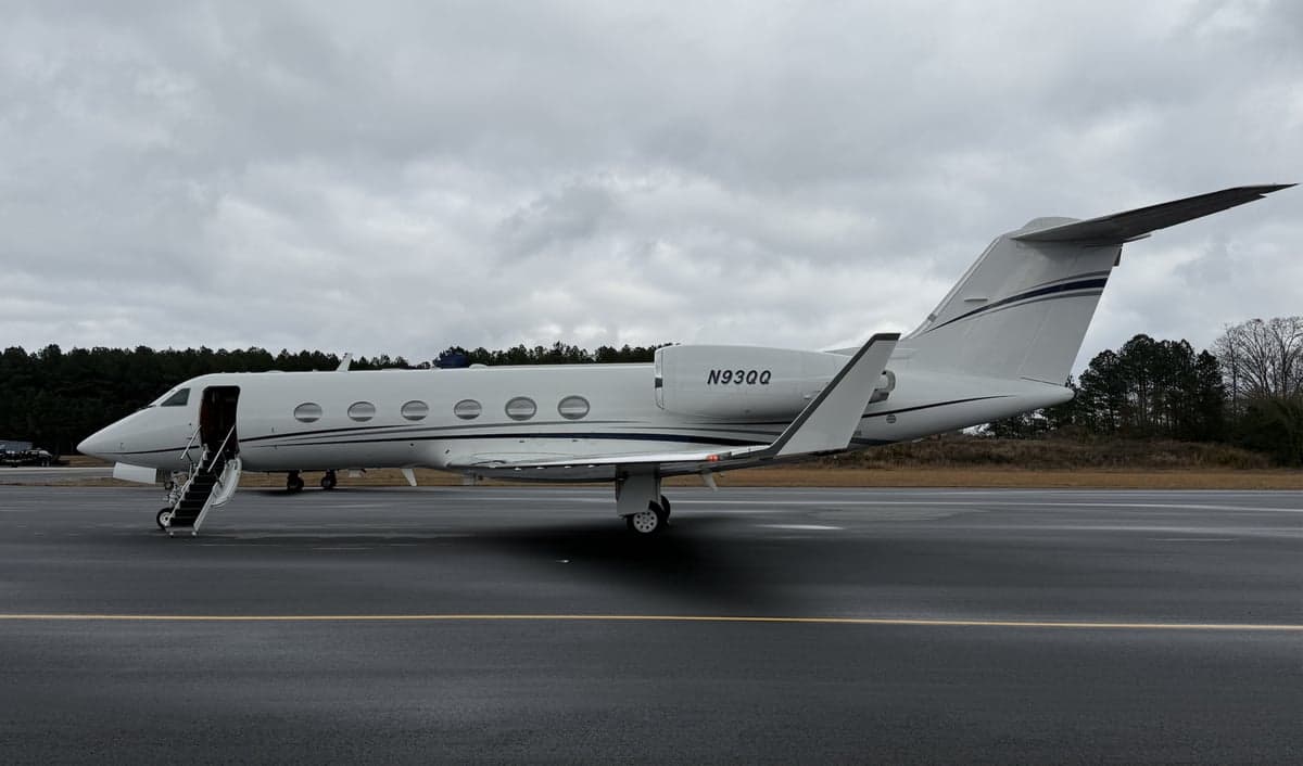 A white Gulfstream jet sits on the tarmac with the airstair door open on a cloudy day.