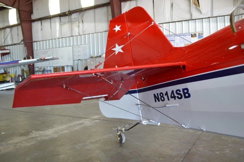 Tail section of a red and white aircraft with stars on the tail and wings, showing the tail number N814SB.
