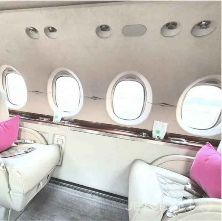 A view of the interior cabin of a business jet, highlighting the oval windows and overhead panel.