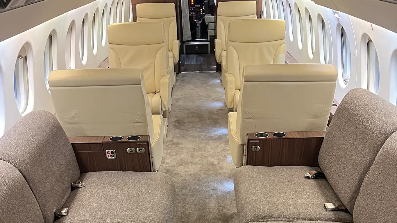 A view from the rear of an aircraft cabin showing beige and grey upholstered seats.