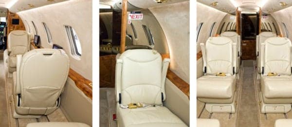 Interior of the aircraft featuring cream-colored leather seats and wood paneling.