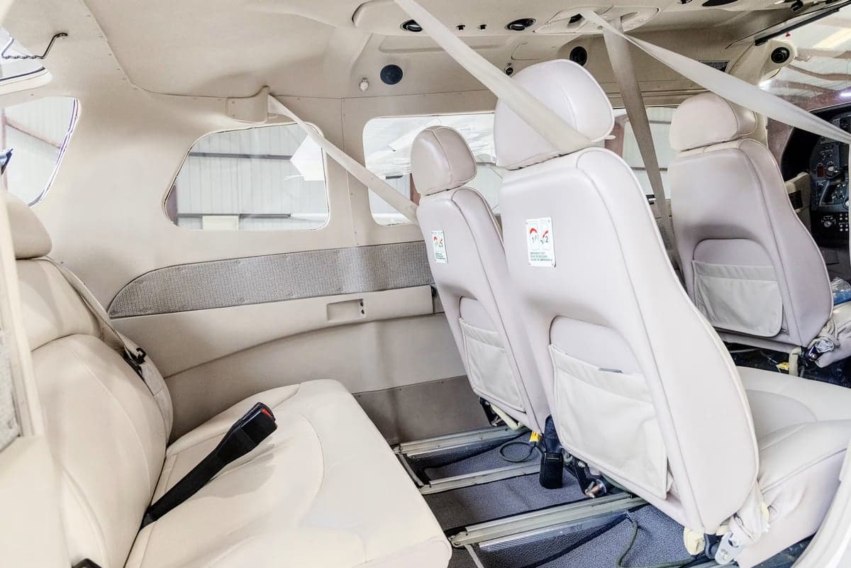 The light beige leather interior cabin of a Cessna Stationair TC, showing multiple rows of seats.