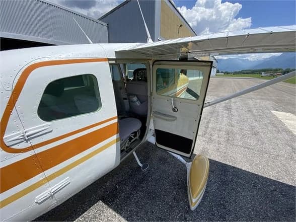 View of the open cabin door of a Cessna 210 Centurion aircraft, showing the interior and exterior.