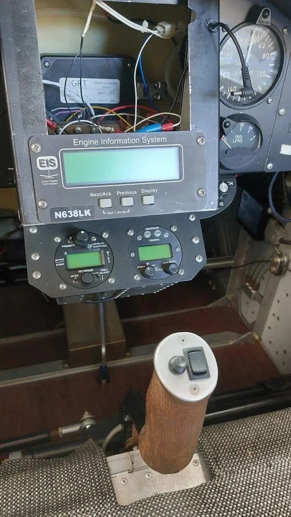 A close-up view of the cockpit instrument panel of an experimental aircraft, showing an Engine Information System display and a control stick.