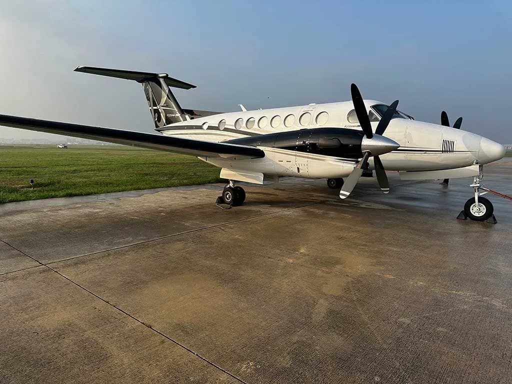 A white and black twin-engine turboprop aircraft parked on a tarmac.