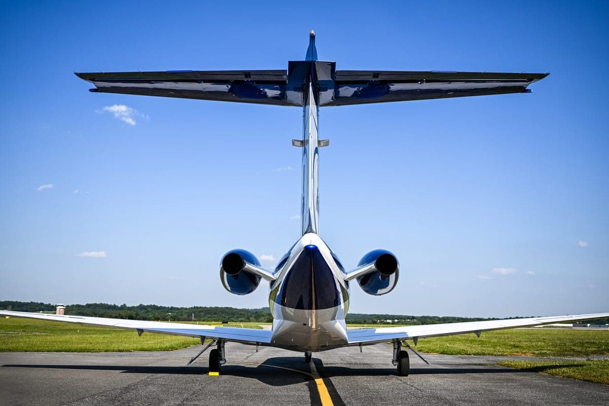Direct rear view of a white and blue Cessna Citation M2 jet on an airport tarmac.
