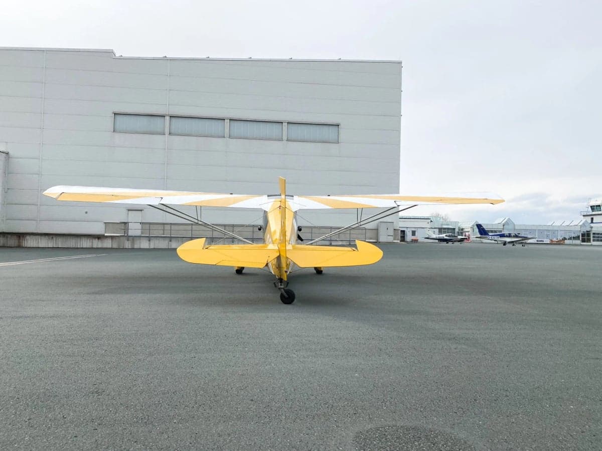 A yellow and white aircraft, D-EIMU, parked on the tarmac in front of a hangar.