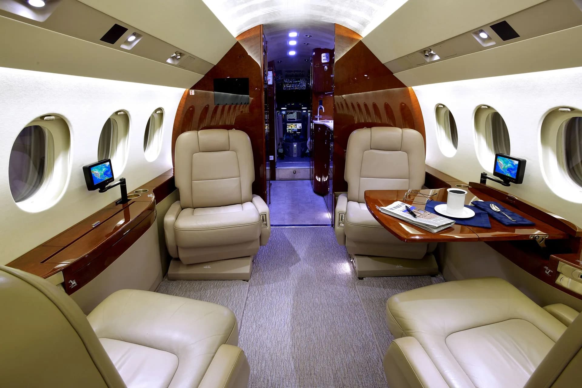 View of the aircraft's interior cabin with leather seats and a table with a cup of coffee and a newspaper.