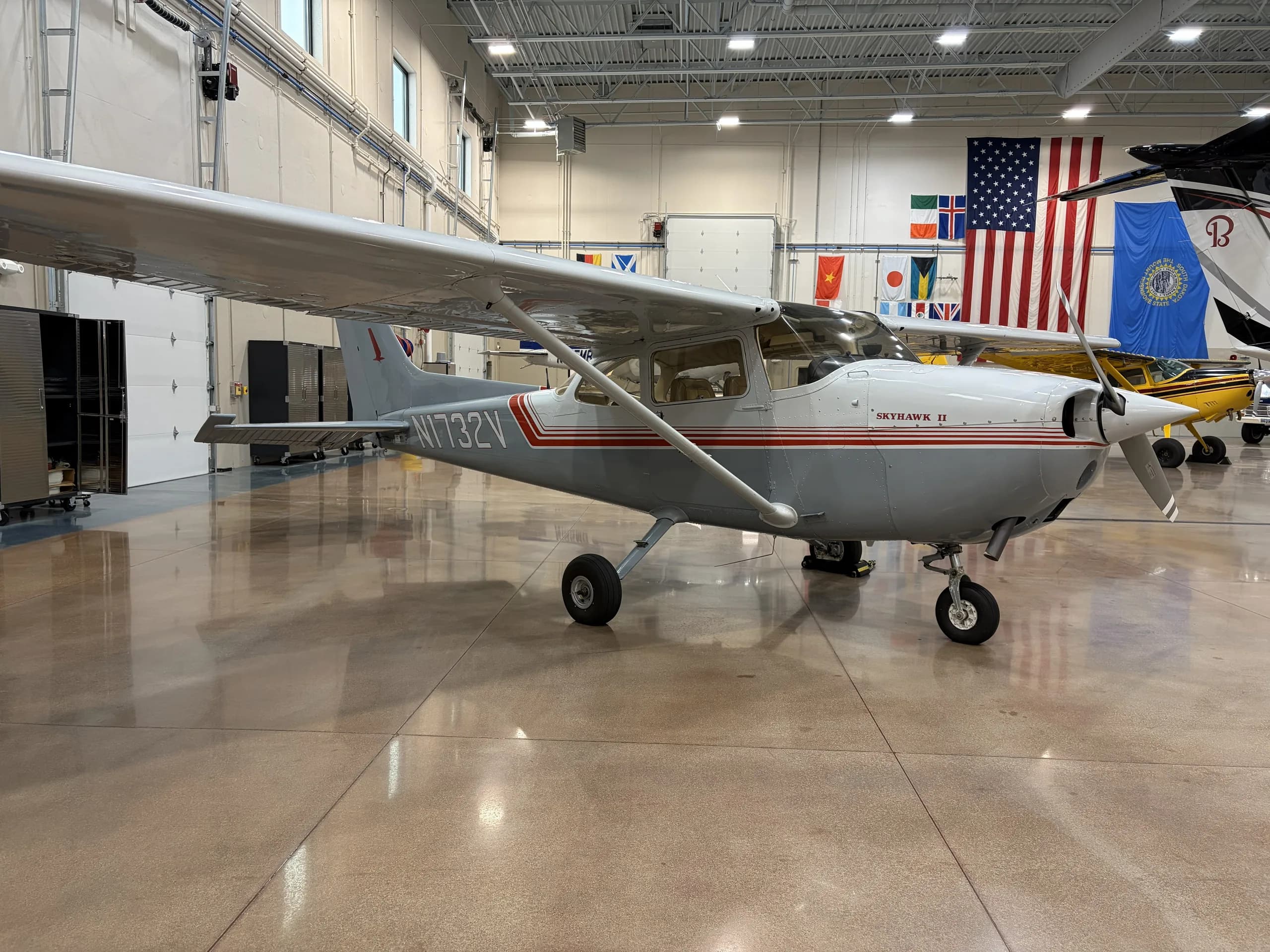 Cessna 172 with gray and red paint scheme in a hangar.