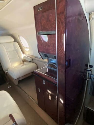 View of the aircraft cabin with leather seats and a magazine on the table.