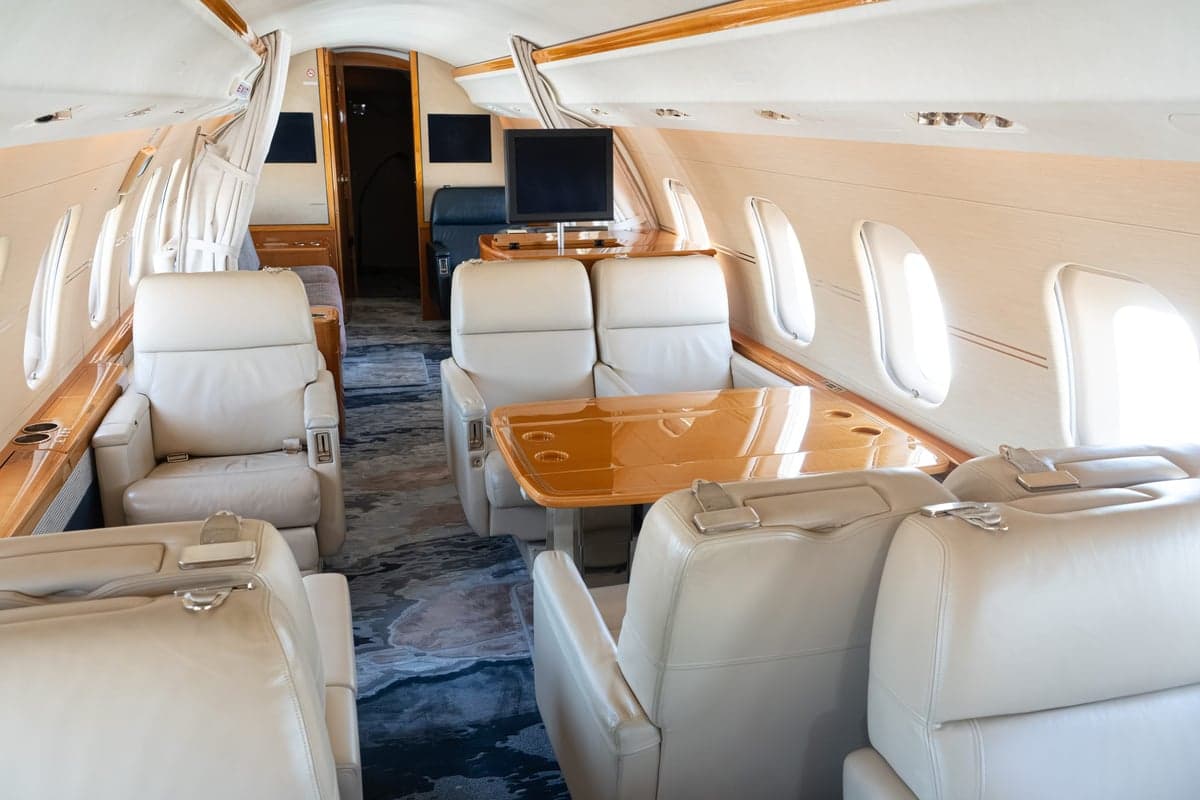 The interior of a Bombardier Global Express with a table and cream leather seats.