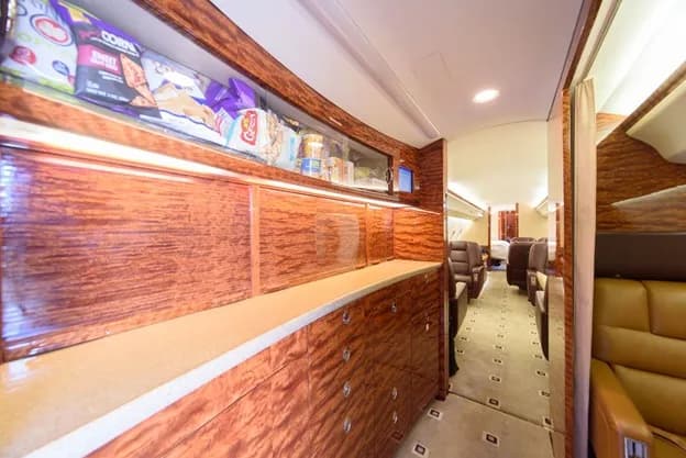 The interior of a Bombardier Challenger aircraft with leather seats and wood trim.