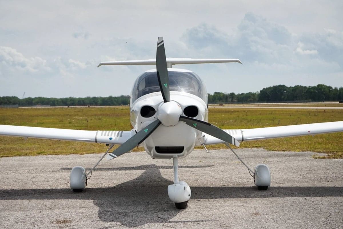 Front view of the white aircraft on the ground with a propeller.