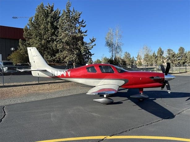 The LX7 aircraft N77VY is parked on the tarmac on a sunny day.