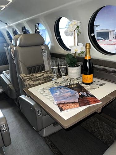 Interior view of the King Air cabin with a table, champagne, and magazines.