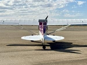 Rear view of a red and white Carbon Cub aircraft on the ground.