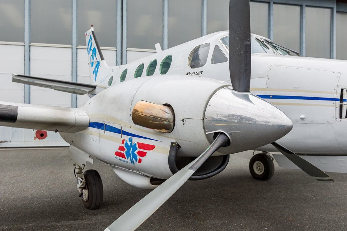 Close-up of the propeller and engine of a Beechcraft King Air C90 aircraft with a white and blue paint scheme.
