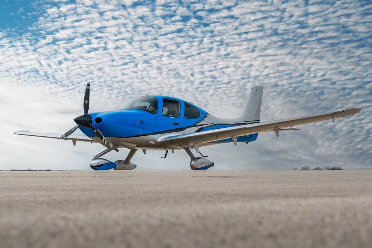 A blue and silver Cirrus SR22 on the ground.