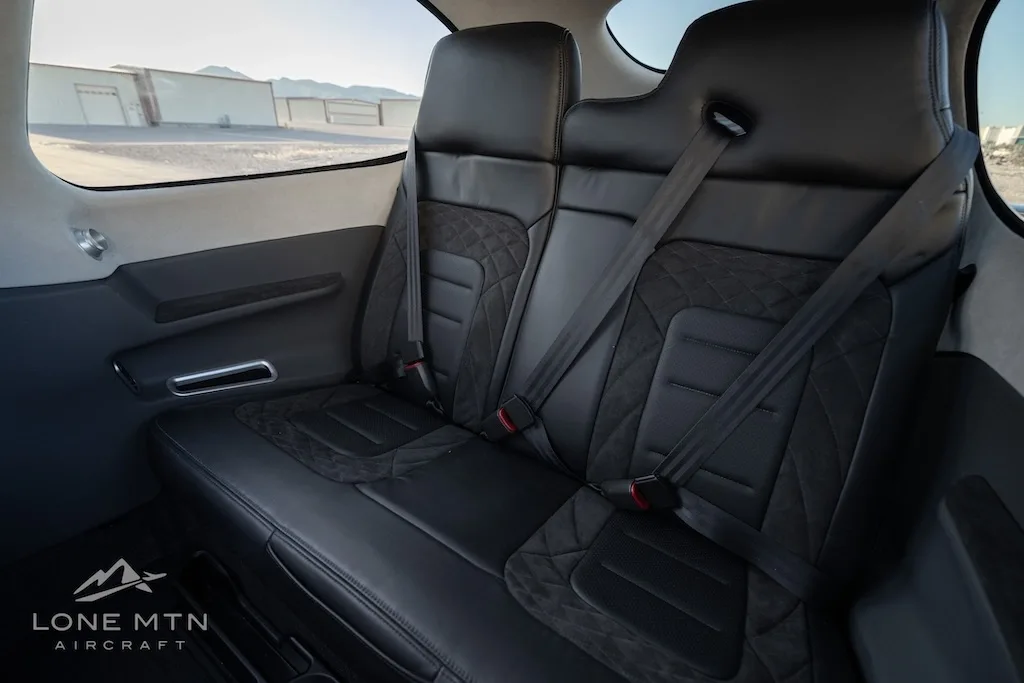 View of the black leather rear seats with quilted stitching inside the aircraft cabin.