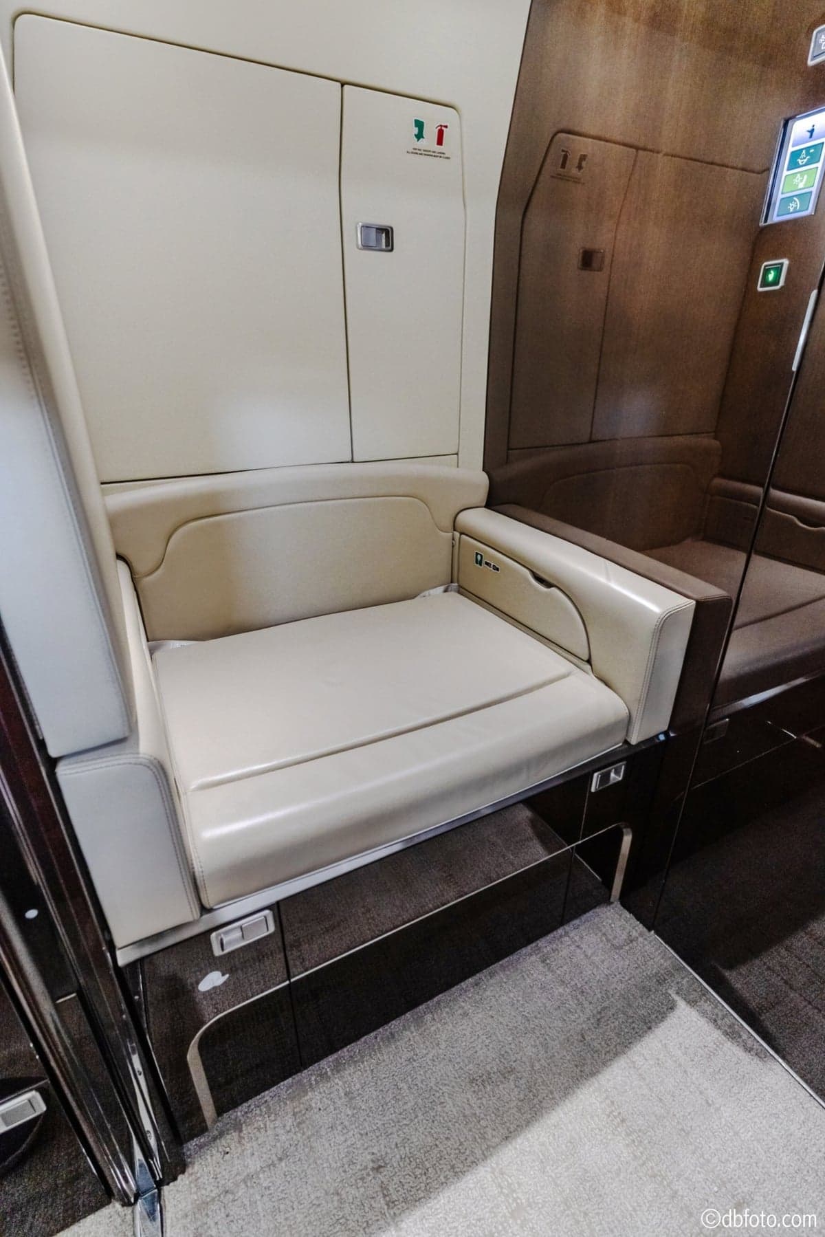 A cream-colored leather seat with dark wood trim inside the aircraft cabin.