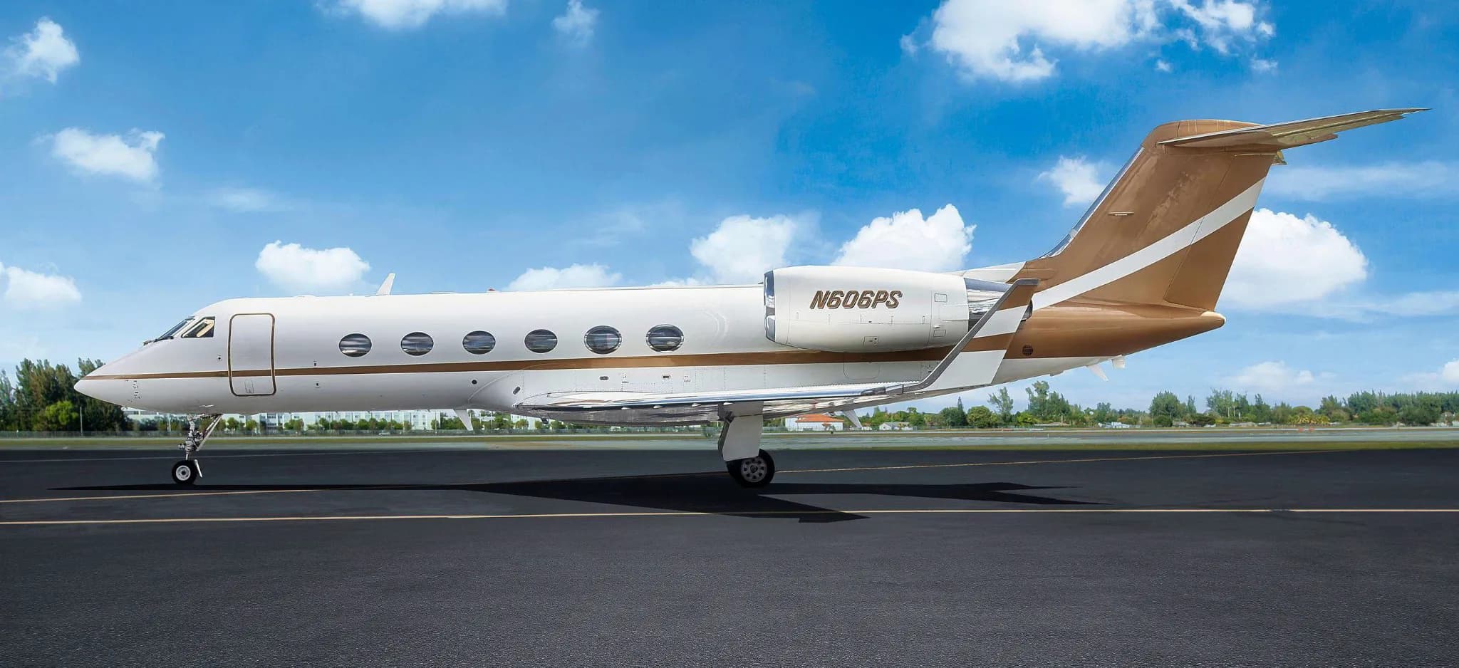 A Gulfstream G550 aircraft, registration N606PS, parked on a tarmac under a blue sky.