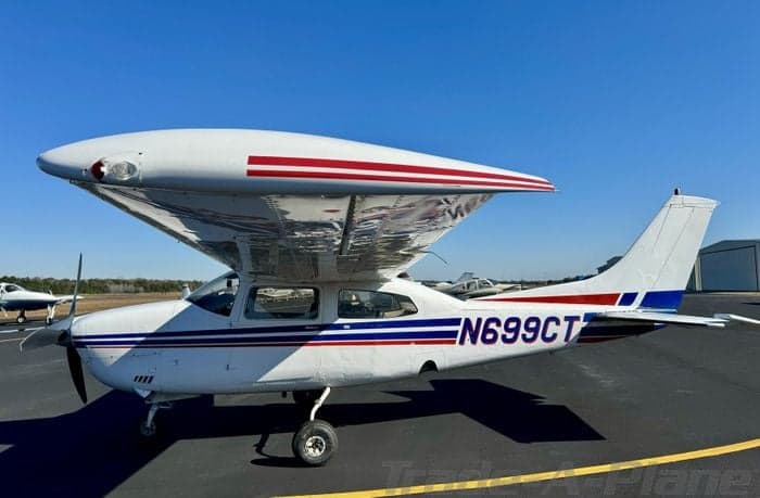 A Cessna 210 Centurion with a white and red paint scheme is parked on the tarmac.